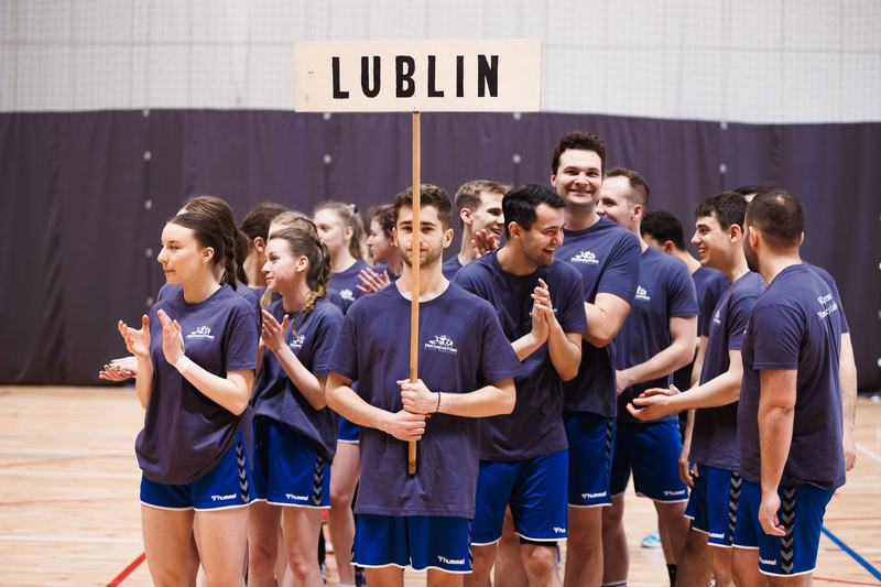Drużyna sportowa w granatowych koszulkach z tabliczką z napisem LUBLIN na hali sportowej