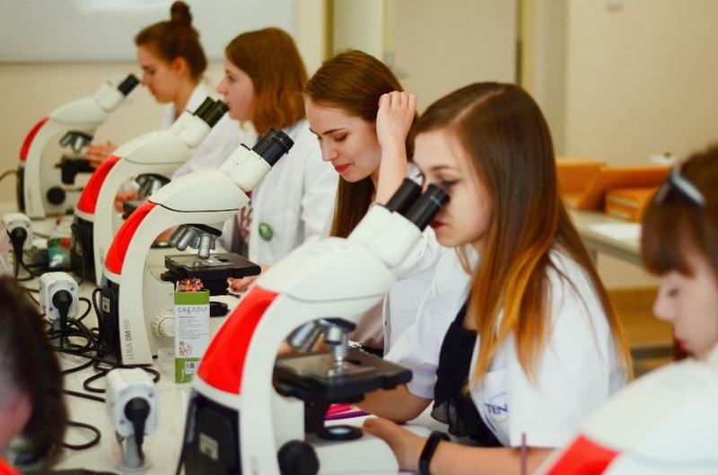 Sześć studentek położnictwa w białych fartuchach trzymających na rękach lalki-symulatory niemowląt